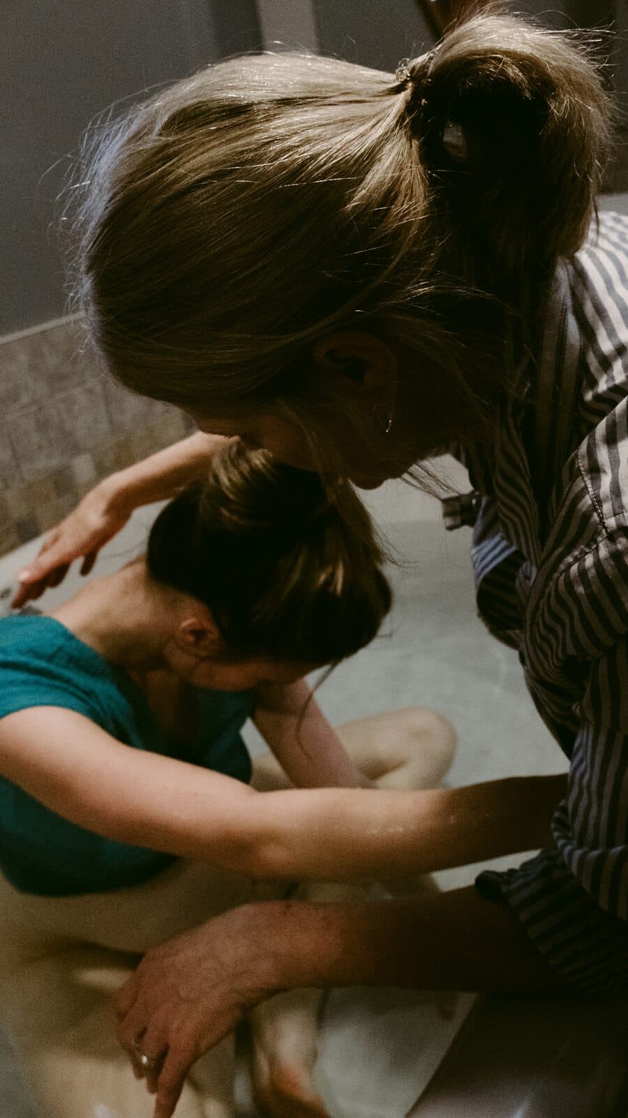 A birth companion leaning in to hold and comfort a labouring woman