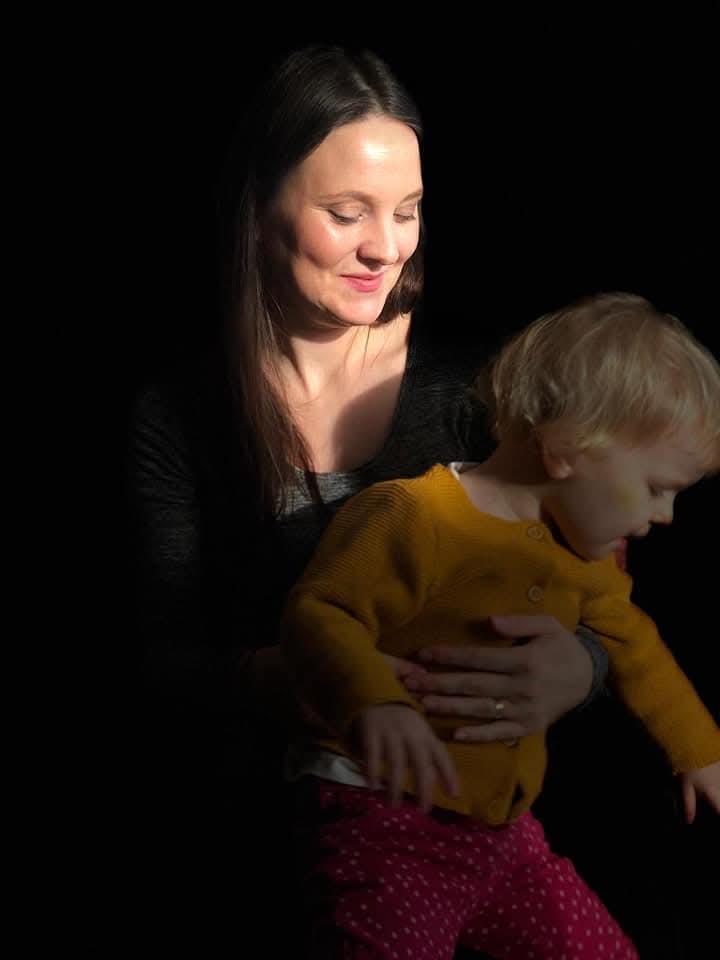 A mother holding her baby close, in soft light