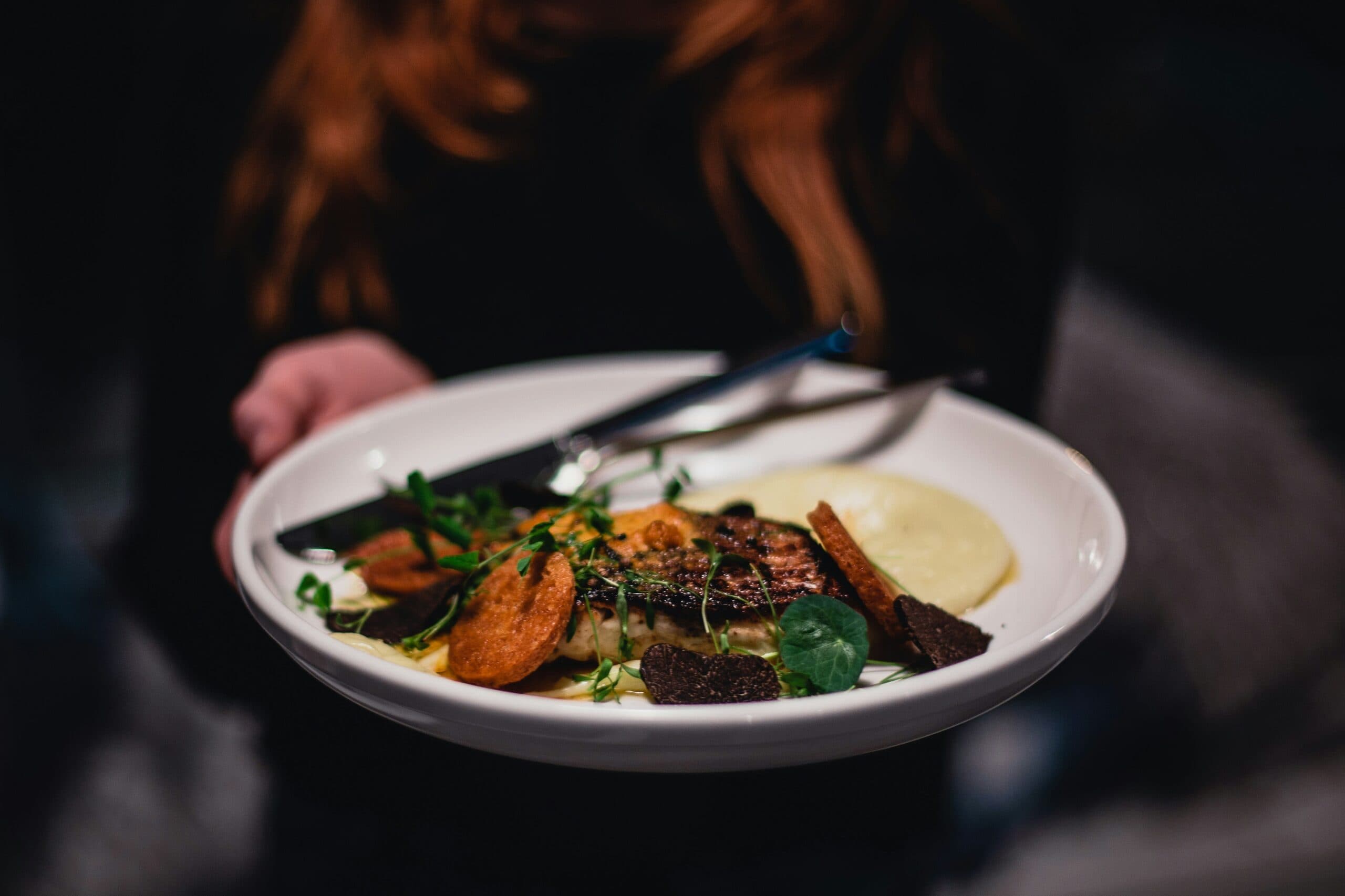 A plated postpartum main course with greens and purée