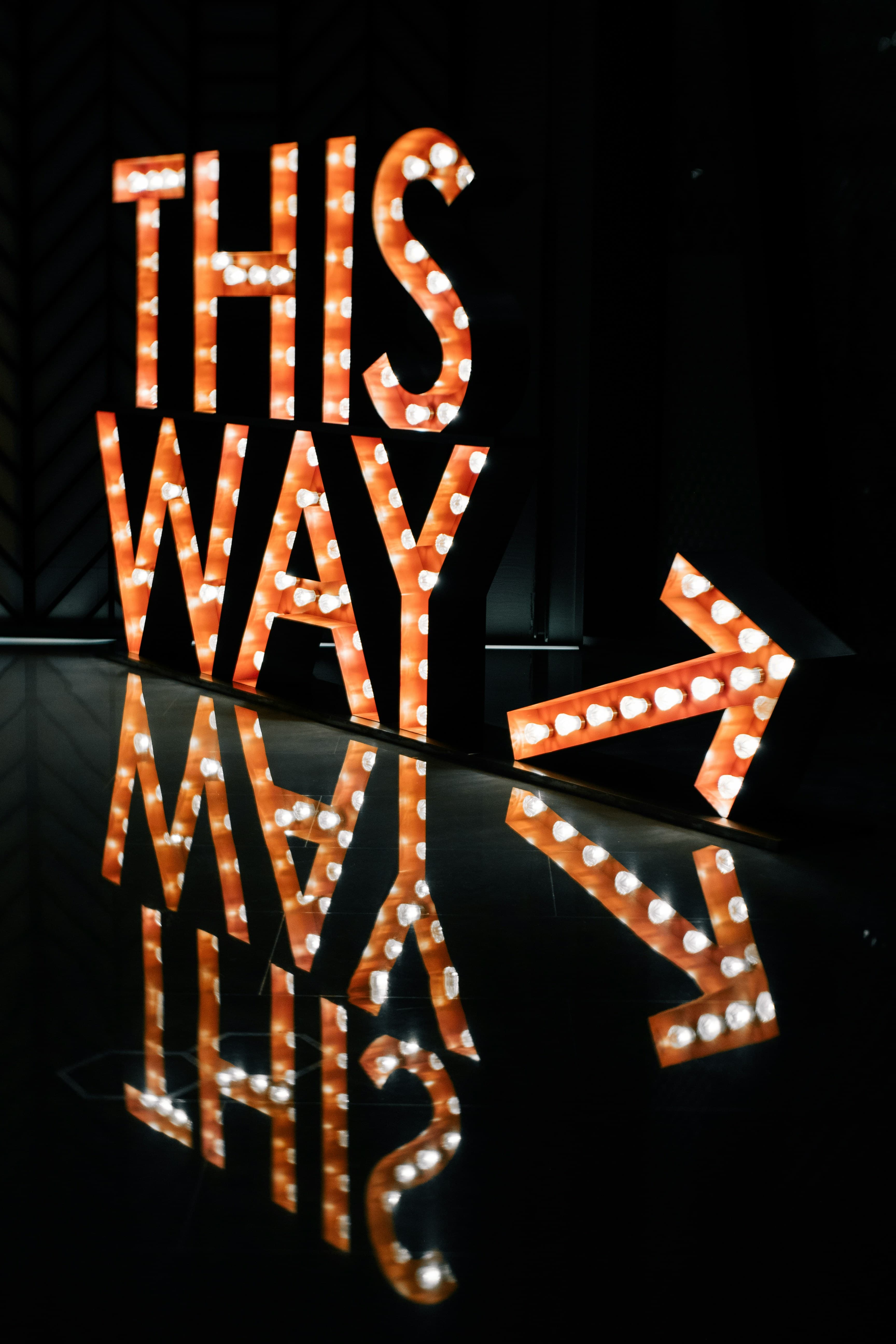 A lit-up THIS WAY sign pointing forward