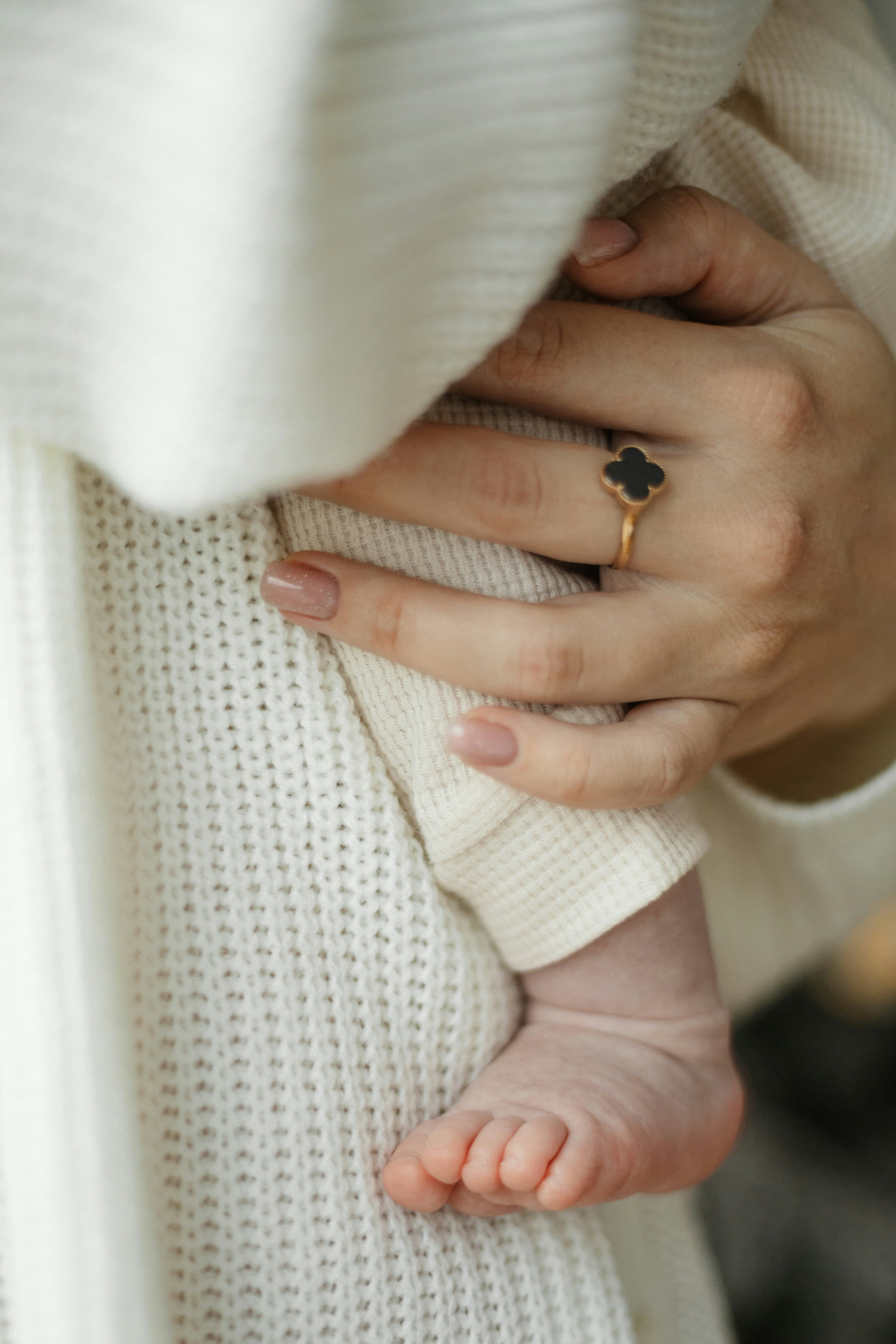 A mother's hand cradling her newborn baby's foot