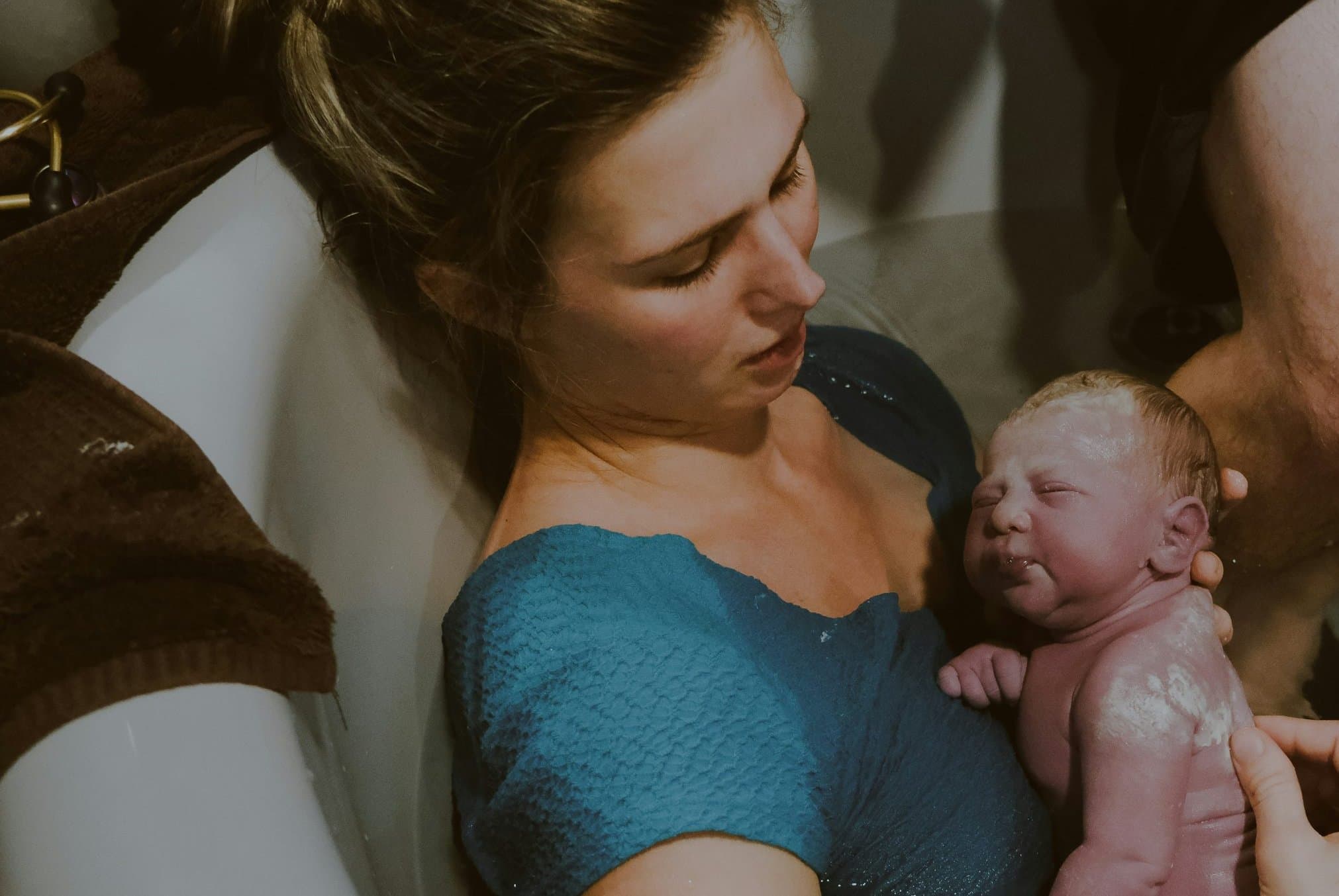 A mother in the birth pool gazing at her newborn